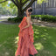 Woman in a coral dress standing on grass with a building in the background