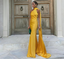 Woman in a yellow evening gown standing in front of a wooden door.